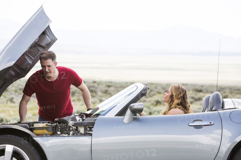 Caucasian man examining car engine at vehicle breakdown