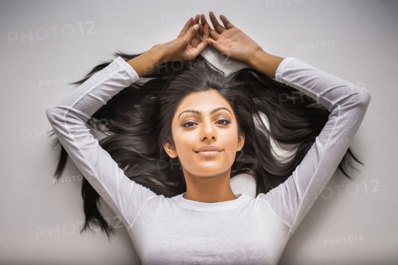 Portrait of smiling Indian woman laying on floor