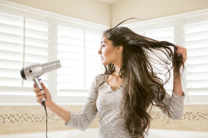 Mixed Race woman drying hair in bathroom