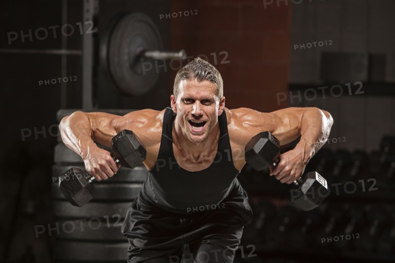 Caucasian man lifting dumbbells in gymnasium