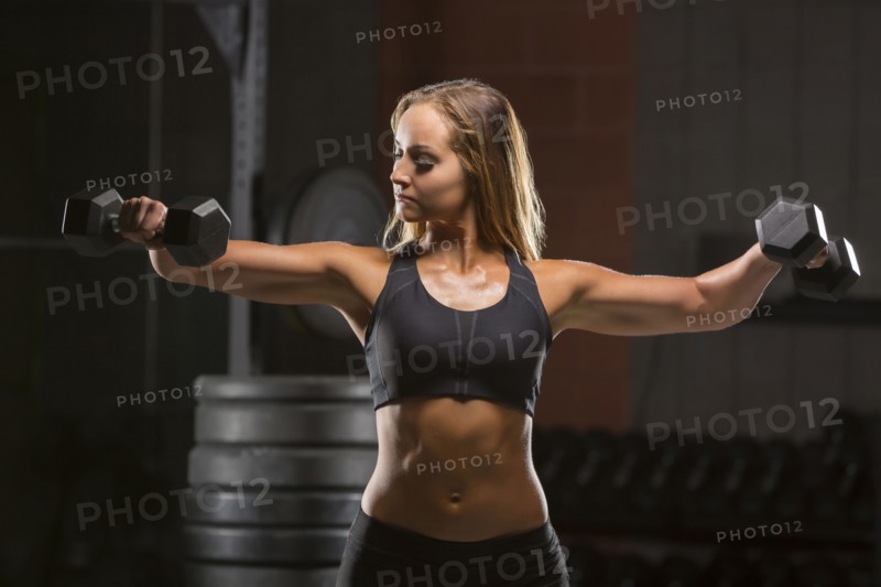 Caucasian woman lifting dumbbells in gymnasium