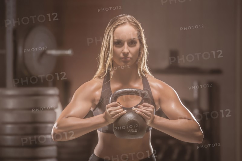 Caucasian woman lifting kettlebell in gymnasium