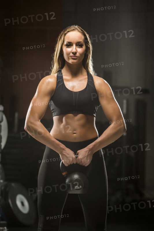 Caucasian woman lifting kettlebell in gymnasium