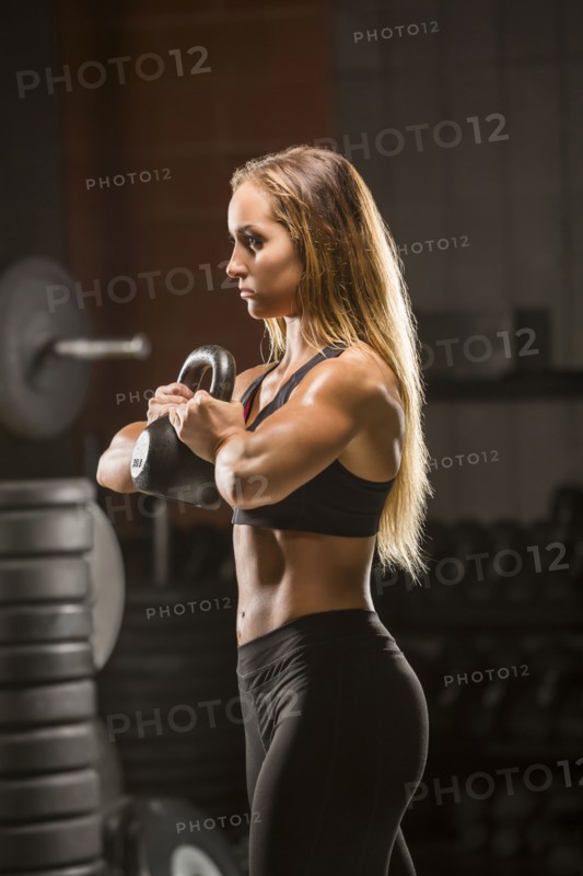 Caucasian woman lifting kettlebell in gymnasium