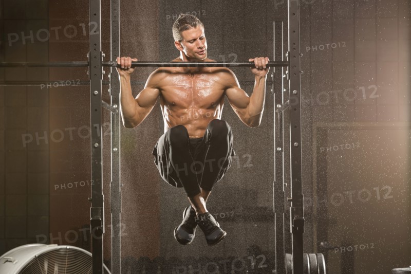 Caucasian man doing chin-up in gymnasium