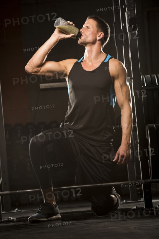 Caucasian man drinking juice in gymnasium