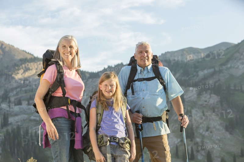 Caucasian grandparents and granddaughter hiking on mountain