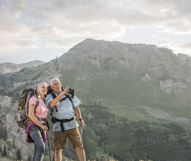 Caucasian couple with binoculars hiking on mountain