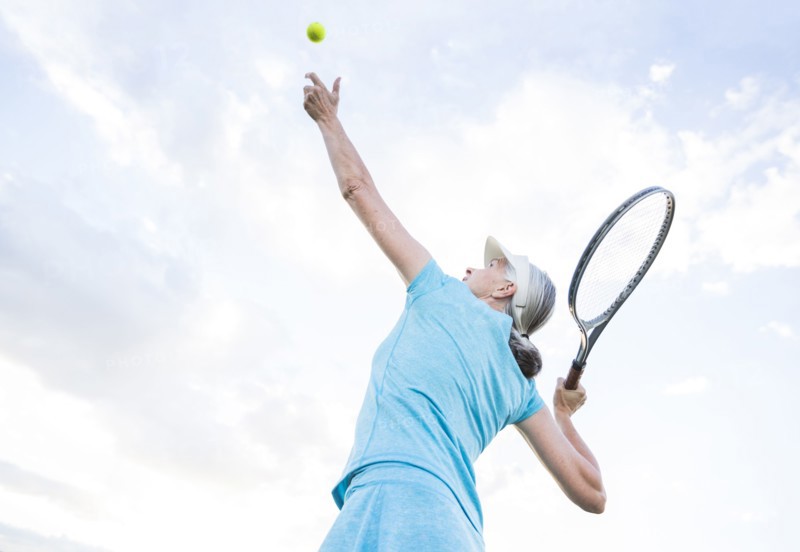 Caucasian woman serving tennis ball