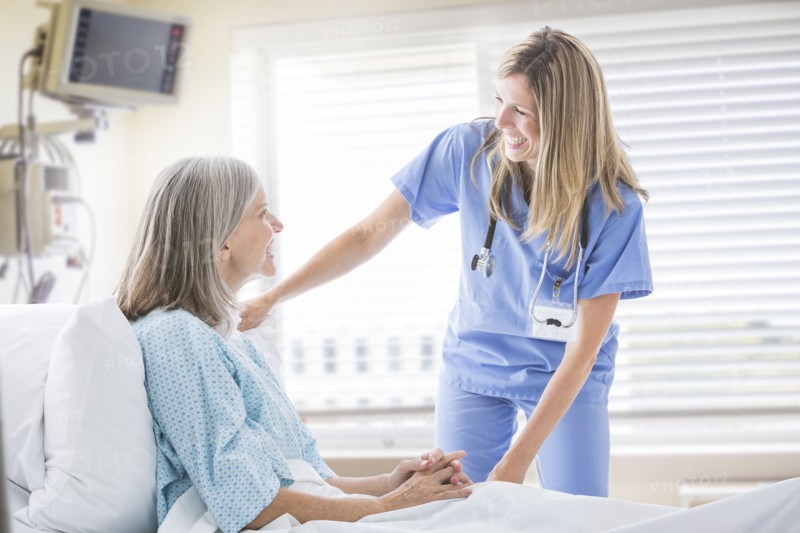 Caucasian nurse talking with woman in hospital bed