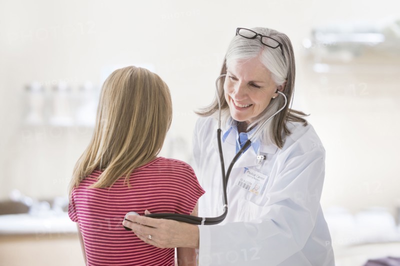 Caucasian doctor listening to chest of girl