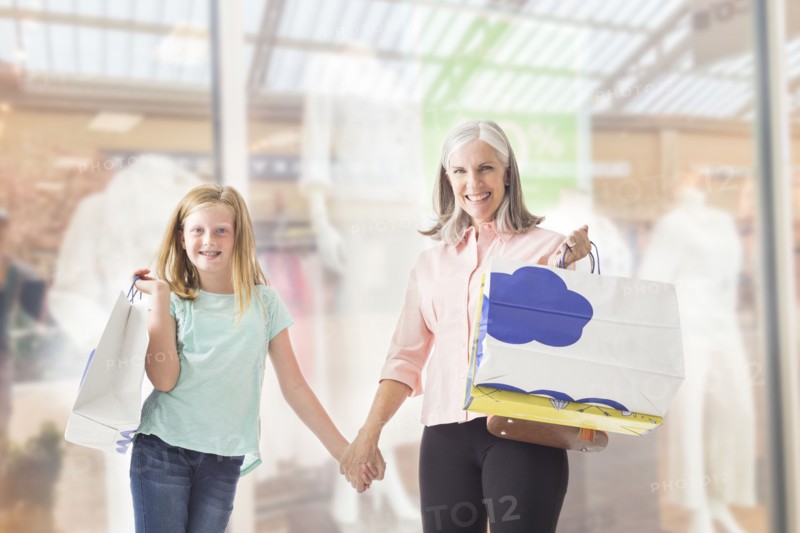 Portrait of Caucasian grandmother and granddaughter holding shopping bags