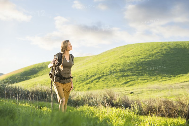 Caucasian woman holding walking stick on hill