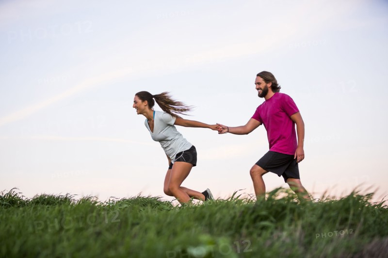 Caucasian woman pulling man on hill