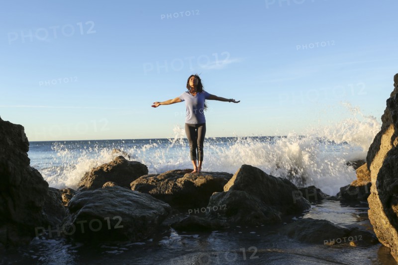 Asian woman standing on rock at beach
