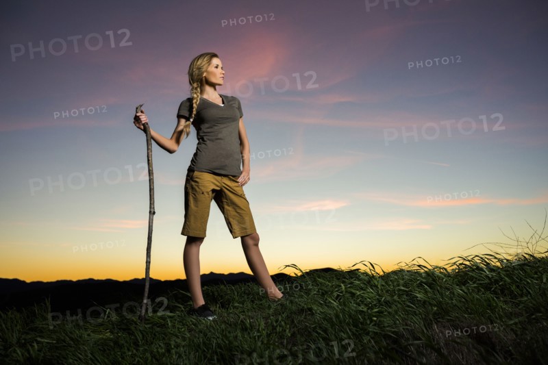 Caucasian woman holding walking stick at sunset