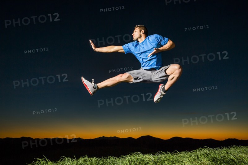 Caucasian man jumping at sunset
