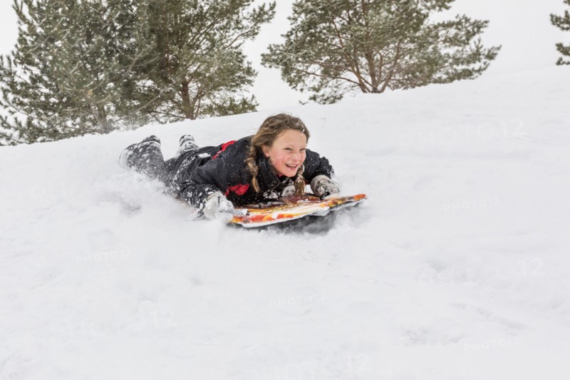 Smiling girl sliding on snowboard on hill in winter