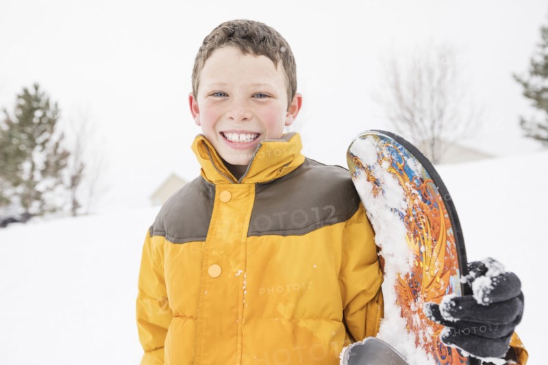 Smiling boy posing with snowboard in winter