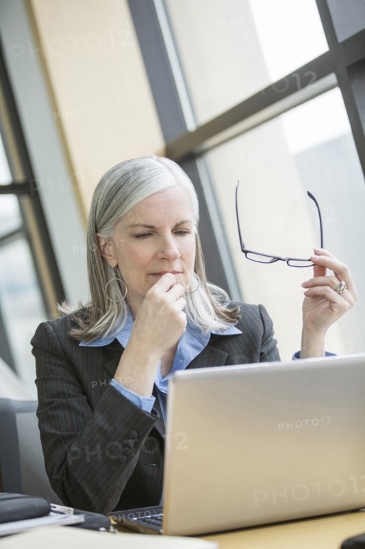 Pensive Caucasian businesswoman using laptop