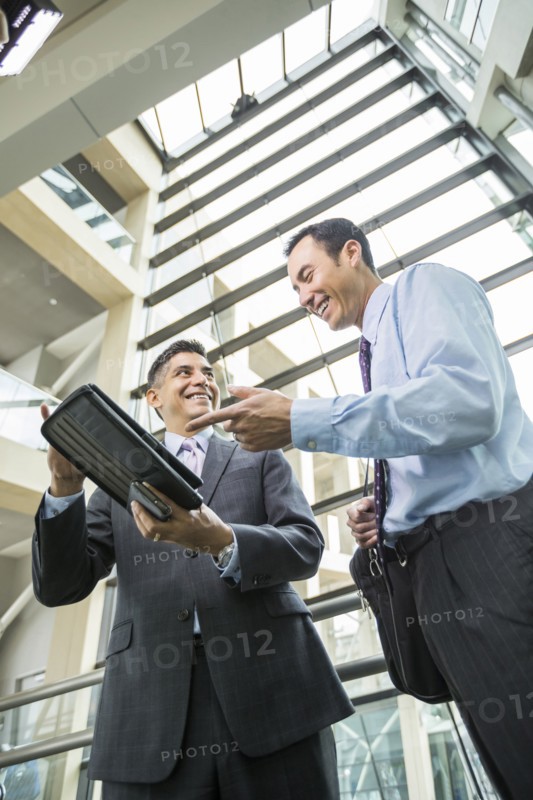 Smiling businessmen using digital tablet in lobby