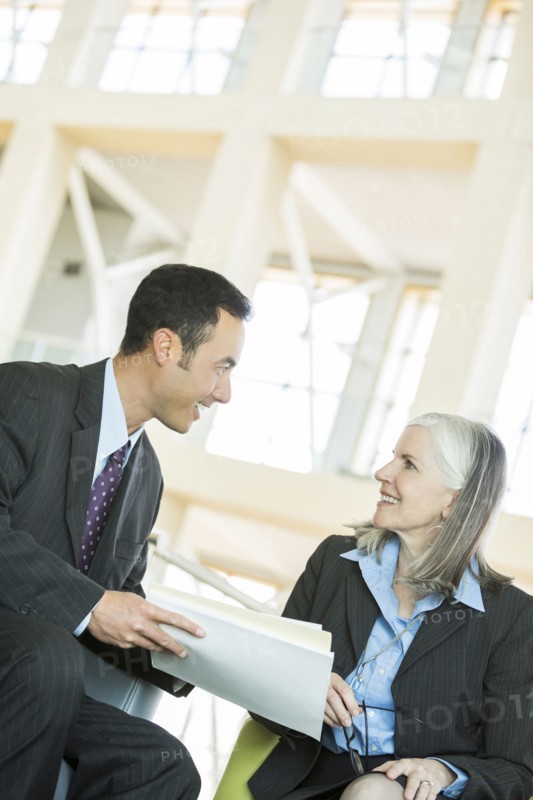 Smiling business people reading paperwork in lobby
