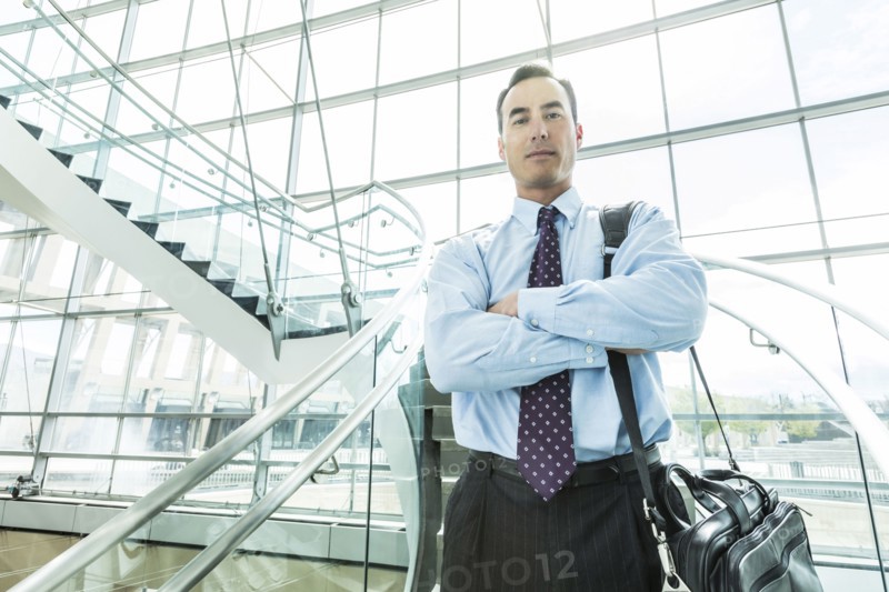 Portrait of serious Mixed Race businessman standing on staircase