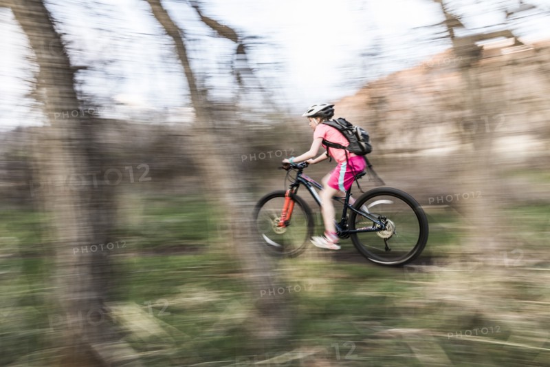 Caucasian girl riding bicycle on forest path