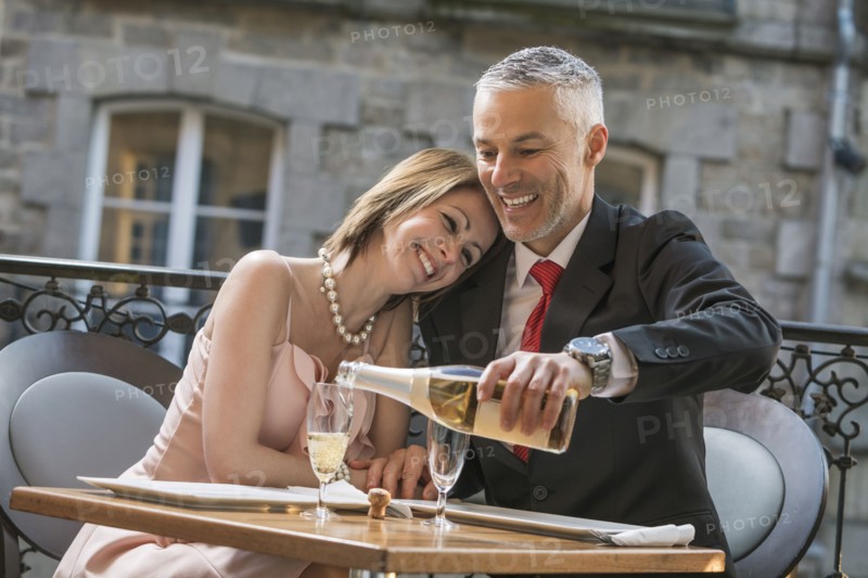 Well-dressed Caucasian man pouring champagne for woman
