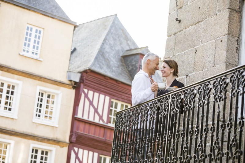 Caucasian couple drinking coffee on balcony in city
