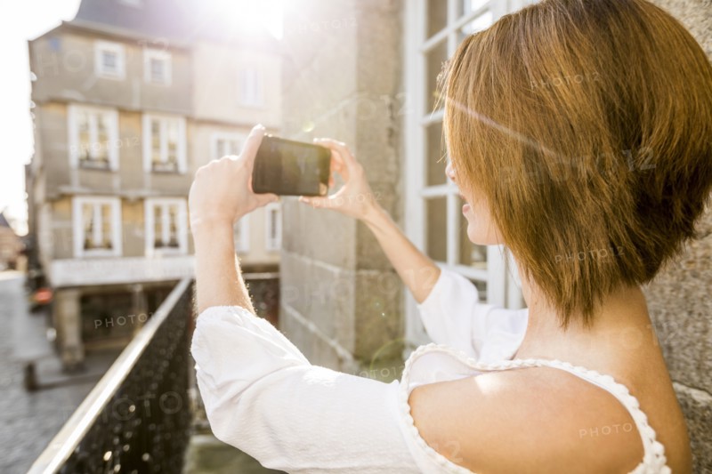 Caucasian woman photographing with cell phone in city
