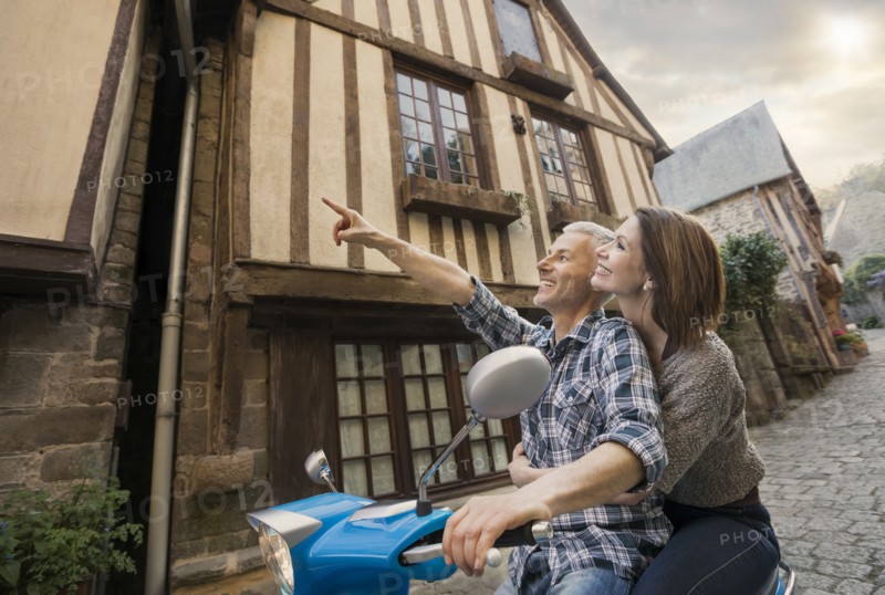 Caucasian couple sightseeing on motor scooter