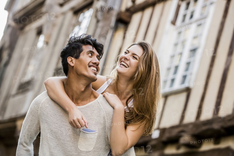 Man carrying woman piggyback in city
