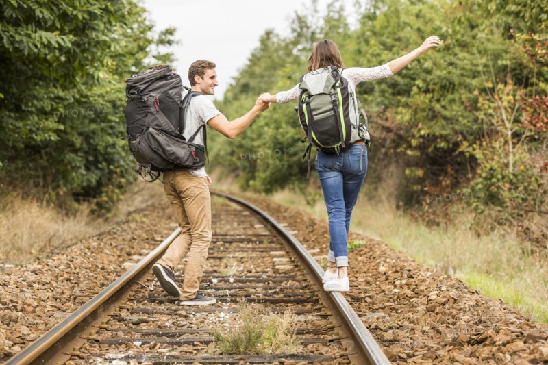Caucasian couple balancing on train tracks