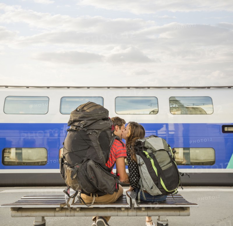 Caucasian couple kissing on bench near train