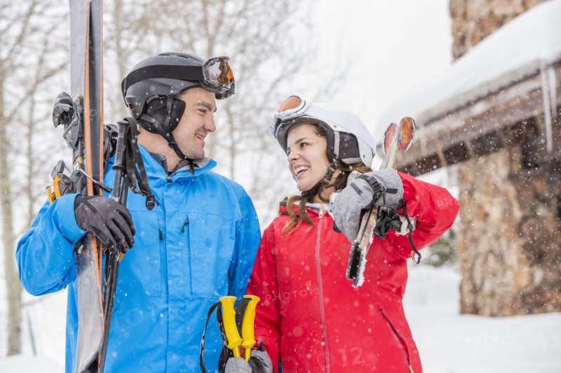 Smiling Caucasian couple carrying skis