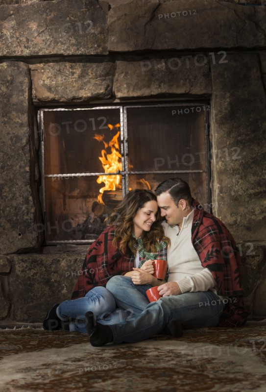 Smiling Caucasian couple cuddling on floor near fireplace