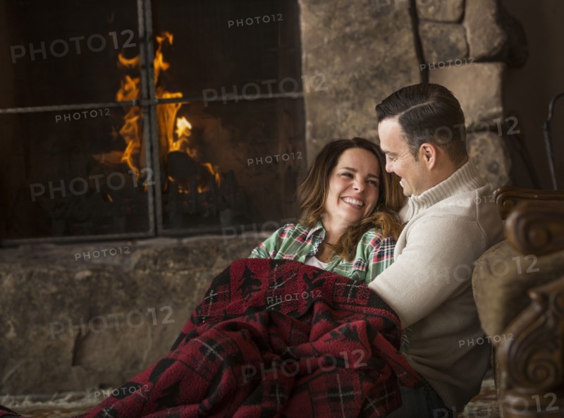 Smiling Caucasian couple cuddling on floor near fireplace