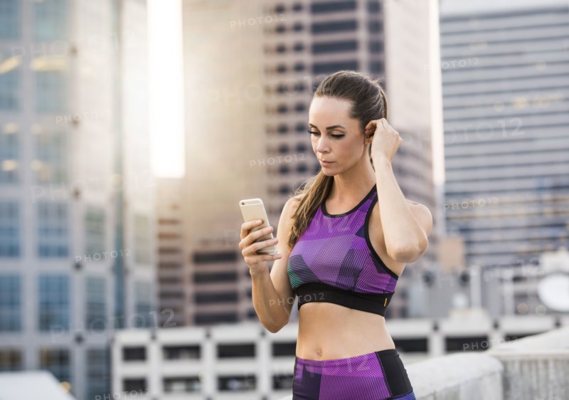 Caucasian woman texting on cell phone on urban rooftop