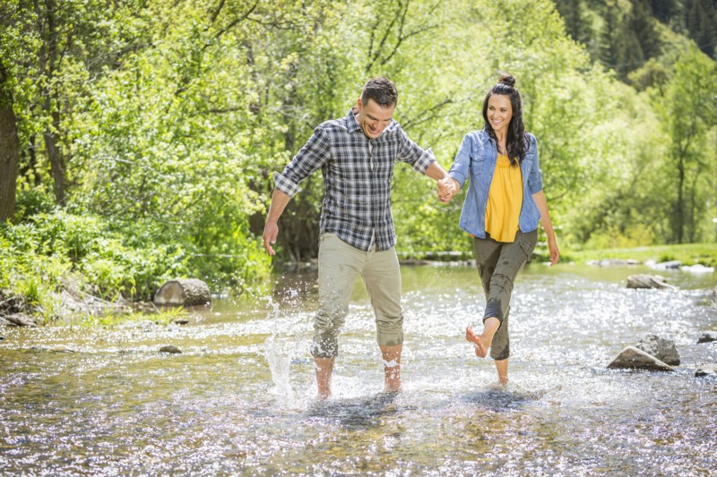 Woman kicking water on man in river