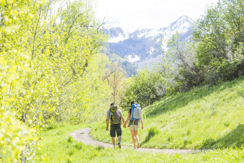 Couple carrying backpacks hiking on path