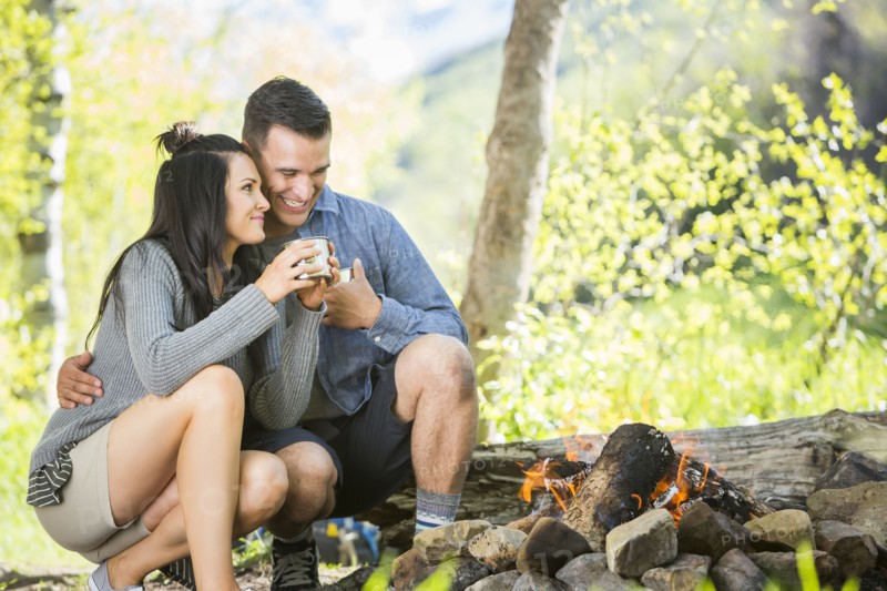 Couple drinking coffee near campfire