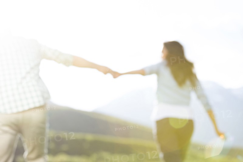 Defocused couple holding hands walking near mountain