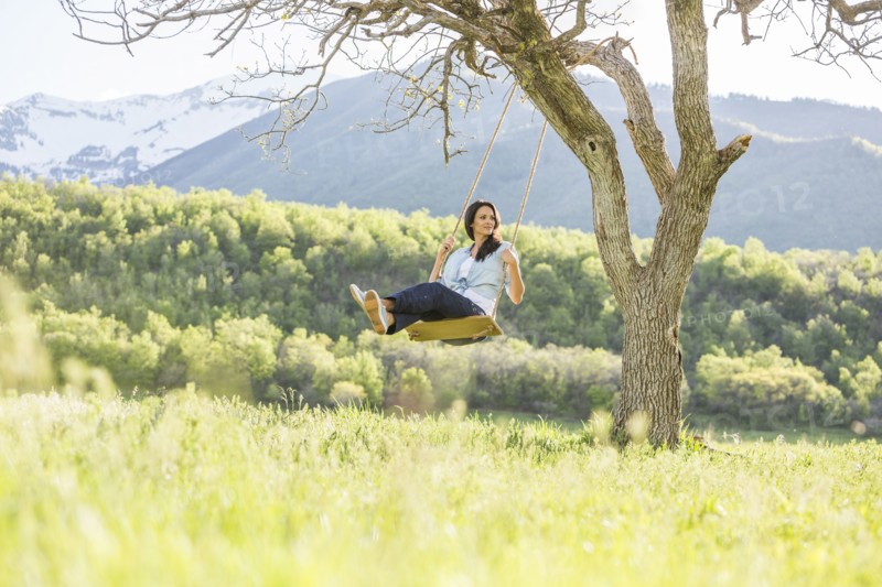 Caucasian woman swinging on tree swing