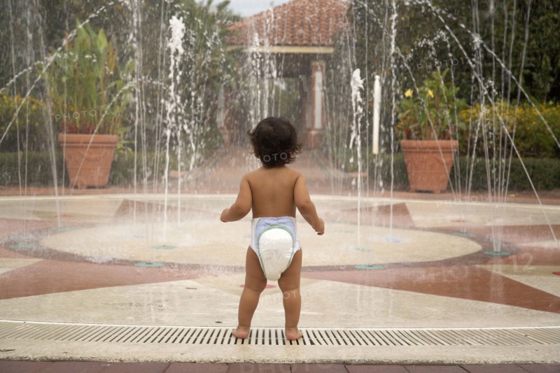 Mixed race baby wearing diaper standing near fountain