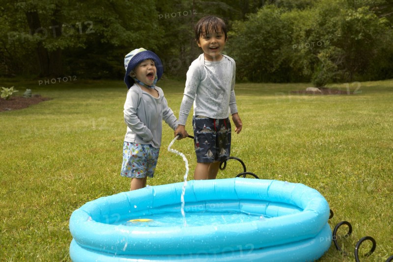 Mixed race children filling inflatable pool