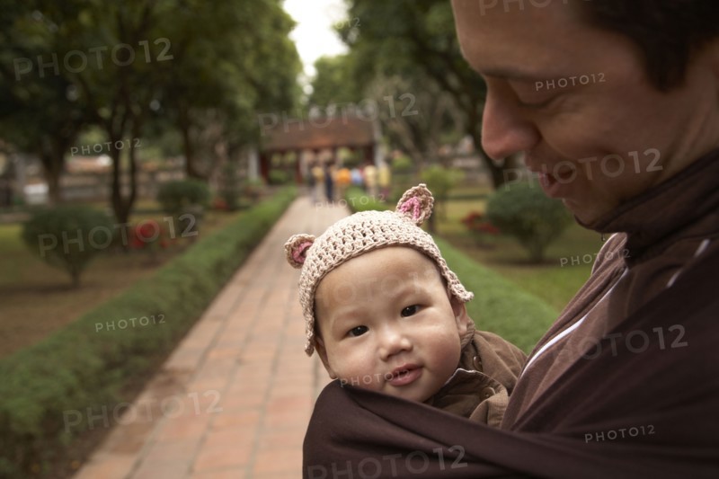Father carrying baby in sling in park