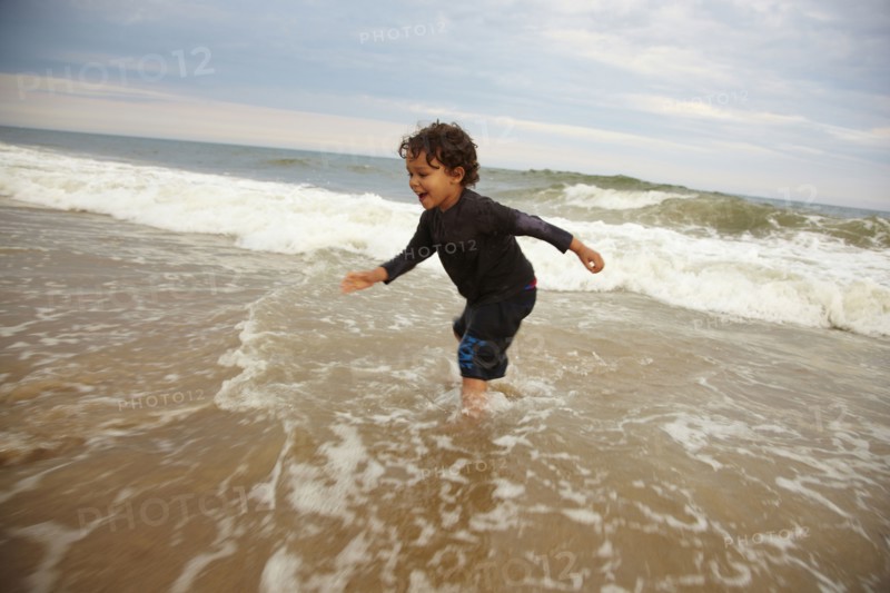 Mixed race boy playing in ocean waves
