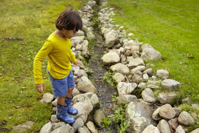 Mixed race boy crossing stream