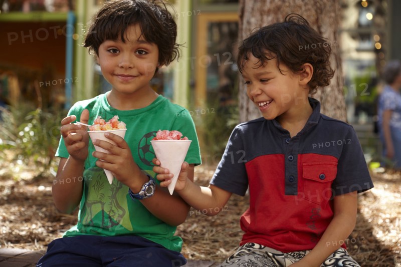 Mixed race boys eating ice cream outdoors